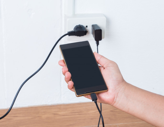 hand-holding-mobile-phone-charging-plugged_50401-64